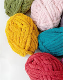 Colorful yarn balls in green, pink, yellow, blue, and red on a white background