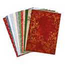 A fan of patterned paper sheets on a white background, with the top sheet in deep red and gold featuring an ornate scroll motif, and the sheets underneath in red, blue, green, beige, and white with holiday patterns.