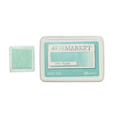 A Manger 49 and MARKET Sea Glass dye ink pad shown with its white plastic casing next to a square sample of the mint green ink.