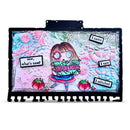 A square mixed-media art plaque featuring a whimsical cartoon girl holding a sewing machine, surrounded by colorful abstract patterns, strawberry motifs, and text labels including 'I came', 'I saw', 'I stitched', and 'sew, what's new?'. The plaque has a black border and is photographed against a plain white background.