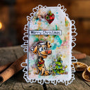 A handmade Christmas greeting card with a white scalloped border, featuring a cartoon Dalmatian wearing a Santa hat, a small decorated Christmas tree, and the text 'Merry Christmas' on a colorful, textured background. The card is displayed on a rustic wooden surface with cinnamon sticks and dried orange slices.