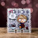 A handmade layered card featuring a cute cartoon girl holding a knitted blanket, set against a white lace-like border with a gray patterned background. The card includes a white cloud tag reading 'yarn love' with a red heart, a small bowl of yarn balls, and a red ball of yarn on a rustic wooden surface with a blurred brown bokeh background.