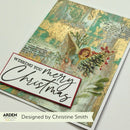 A handmade Christmas greeting card featuring a collage design with a gold-leaf textured background, vintage book text, a winged angel, red berries, and a white 'Wishing You Merry Christmas' banner. The card is photographed on a white surface with branding text 'ARDEN' and 'Designed by Christine Smith' at the bottom.
