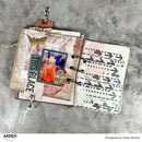 Open notebook with decorative pages and stickers on a gray surface, designed by Katie Pertiet.