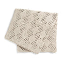 A folded cream-colored knit blanket with an openwork geometric pattern, displayed on a clean white background.