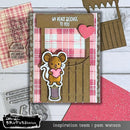 Card with a mouse holding a heart and plaid design, surrounded by crafting tools on a wooden surface.