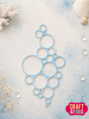 A light blue plastic ring cutter or stencil with multiple nested circular cutouts, displayed on a textured light blue and white background with decorative seashells and coral. A 'CRAFT & YOU' brand logo is visible in the bottom right corner.