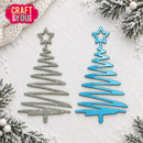 Two Christmas tree-shaped metal dies, one in silver and one in bright blue, displayed on a textured white background with festive pine branches and snow around the edges. A pink 'Craft & You' logo is in the top-left corner.