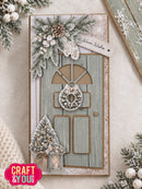 A handmade Christmas greeting card featuring a weathered blue-green door with a wreath, evergreen branches, pinecones, a small tree, and a lantern, styled on a neutral background with a 'Warm Wishes' tag. A 'CRAFT & YOU!' logo is visible in the bottom-left corner.