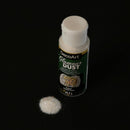 A bottle of DecoArt Glamour Dust glitter powder with a small pile of white sparkling dust in front of it, set against a solid black background.