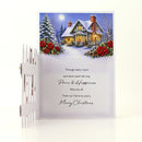 A Christmas greeting card with a winter village scene illustration and a white picket fence prop on a clean white background.