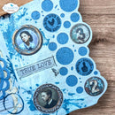 Decorative paper with blue circular designs, portraits, and text on a wooden surface.