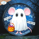 A circular Halloween-themed craft plaque or sign featuring a cute white ghost mouse with pink ears and feet, holding an orange jack-o'-lantern candy bucket. The plaque has a dark blue starry night background and is shown against a spooky outdoor scene with bare trees.