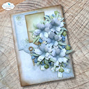 A handmade scrapbook card featuring layered paper flowers in pale blue, white, and sage green, with a small vintage key charm detail, displayed on a rustic wood slice background. The brand logo 'Elizabeth craft designs' is visible in the top-left corner.