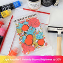 A Gelelf Light Amplifier sheet with a colorful floral design, displayed on a white surface surrounded by Gelelf acrylic paints, a rubber stamp, and a hammers tool.