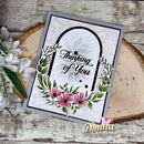 A handmade greeting card with a floral arch design and the words 'Thinking of You' in black script, styled on a rustic wood slice with white flowers beside it. A 'Donna' watermark appears at the bottom right.