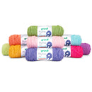 A stack of eight Gründl Pluma uni yarn skeins in assorted colors, including green, orange, pink, blue, purple, yellow, and magenta, arranged on a clean white background.