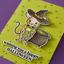 Halloween-themed card with a cat in a witch hat and cauldron on a green background.