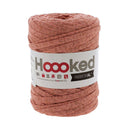 A skein of Hooked RIBBON XL yarn in a dusty rose pink color, wrapped with a white paper label showing the brand 'Hooooked'.
