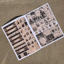 An open booklet or sheet of decorative paper stickers with vintage-style labels, tags, and illustrated motifs, photographed on a textured tan fabric background.