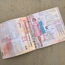 An open vintage sewing pattern book or paper booklet laid on a beige fabric surface. The pages show fashion illustrations, measurement tables, and text including 'Creativity sewing paper' and 'Mider collar.