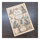 A book titled 'Fairy Fantasia' with vintage-style fairy illustrations, photographed at an angle on a dark wood surface.