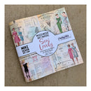 A packaged set of vintage-style mixed media art papers titled 'Sew Lovely' by Mike Deakin Art, shown on a textured beige fabric background. The paper pack features retro sewing illustrations of women in dresses and a central white label with pink and black text.