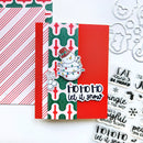 A handmade Christmas greeting card with a red and green patterned background, a red vertical panel, a die-cut snowman ornament, and the phrase 'HO HO HO let it snow' in black script. The card is styled on a white surface with patterned paper, metal cutouts, and clear stamp sheets nearby.