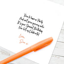 Orange pen on a white surface with handwritten birthday message.