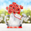 Red flowers in a watering can with a 'Birthday Wishes' tag against a blurred outdoor background