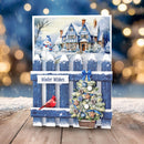 A square winter-themed greeting card displayed on a wooden surface with a blurred festive background. The card features a snowy house scene with a snowman, a blue picket fence, a decorated Christmas tree, a red cardinal, and the text 'Winter Wishes'.
