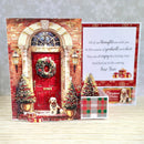 A festive New Year greeting card set displayed on a light wood surface. The main card features a detailed 3D-style illustration of a red front door with a wreath, lit lanterns, two decorated Christmas trees, and a small dog sitting at the doorstep.