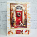 A handmade Christmas greeting card featuring a festive front door scene with a red door, wreath, decorated trees, and a small dog sitting at the door. The card is displayed on a white surface against a light gray brick-patterned background, with two red and gold ribbon bows at the bottom.