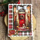 A scalloped holiday greeting card featuring a festive front door scene with a red door, wreath, garlands, plaid borders, and a small dog portrait. The card is photographed on a rustic wood surface with evergreen branches and red berries nearby.
