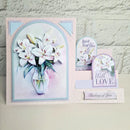 A handmade layered greeting card set featuring white lilies in a glass vase, with text elements reading 'Just for You', 'With LOVE', and 'Thinking of You', displayed against a light brick wall background.