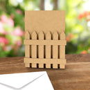 Cardboard fence model on a wooden surface with a blurred floral background