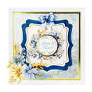 A square handmade greeting card featuring layered navy blue and white scalloped frames, a blue bow at the top, blue and yellow floral embellishments, and a central circular gold-bordered label reading 'Love & Kisses'.