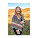 Woman wearing a colorful striped shawl in a natural setting with mountains and blue sky.