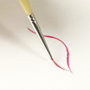 A close-up of a fine paintbrush with a pale yellow handle and silver ferrule, drawing a thin red line on a plain white background.