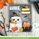 A handmade Halloween greeting card featuring a cute ghost character in a witch hat, a cauldron with orange potion, books, spiderwebs, and the text 'BREWING UP SOME HALLOWEEN FUN'. The card is displayed on a white wood background with autumn-themed decorative props.