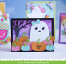 A handmade Halloween greeting card featuring a cute white ghost with a light blue bow, surrounded by orange, pink, and light blue paper pumpkins with green stems. The card has a black frame and a purple background with a black tree silhouette.