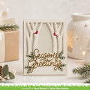 A handmade layered card with a forest theme, featuring laser-cut tree branches, two small red birds, green pine branches, and the words 'Seasons Greetings' in gold. The card is displayed on a white surface with a warm white ceramic candle holder and a kraft gift box in the background.