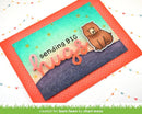 A handmade greeting card featuring a watercolor-style teal and beige background, a dark purple textured hill, the phrase 'sending BIG hugs' in pink script, and a cartoon brown bear. The card is layered over a bright coral-orange patterned cardstock and photographed on a white surface with decorative string lights.
