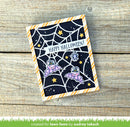 A handmade Halloween greeting card featuring a spiderweb design, purple bats, and the text 'HAPPY HALLOWEEN!' on a dark background, styled on a rustic wooden surface.