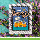 A handmade Halloween greeting card with a scalloped black border, featuring the words 'spooky hugs' in orange script over a blue starry background, with three orange jack-o'-lantern pumpkins wearing purple witch hats. The card is displayed on a striped white and gray background with purple flowers around it.