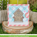A handmade Christmas greeting card featuring a gingerbread house with the text 'HAVE A SWEET CHRISTMAS' on a light blue and white gingham background, styled on a wood slice with cacti in the background.