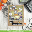 A handmade scrapbook card featuring three illustrated cats in witch hats around cauldrons and books, styled on a white wood background with Halloween-themed props and stamp blocks.