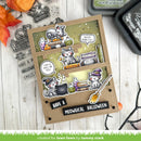 A handmade Halloween-themed card or scrapbook page featuring cartoon cats with books, potion bottles, a cauldron, and broomstick stickers, displayed on a white wood surface with crafting tools around it.