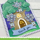 A handmade layered card featuring a whimsical treehouse scene with three blue-and-white fairy cutouts perched on lanterns, a brown treehouse with a yellow window and door, green textured tree leaves, a purple starry sky, and a blue banner reading 'thank you.' The card is photographed on a white wood surface.