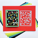 A handmade holiday card layout on a bright red cardstock base, featuring a black square panel with colorful Christmas string lights and a silver metal die-cut frame showing matching leaf and light motifs. Stamped text reads 'Deck of Halls.